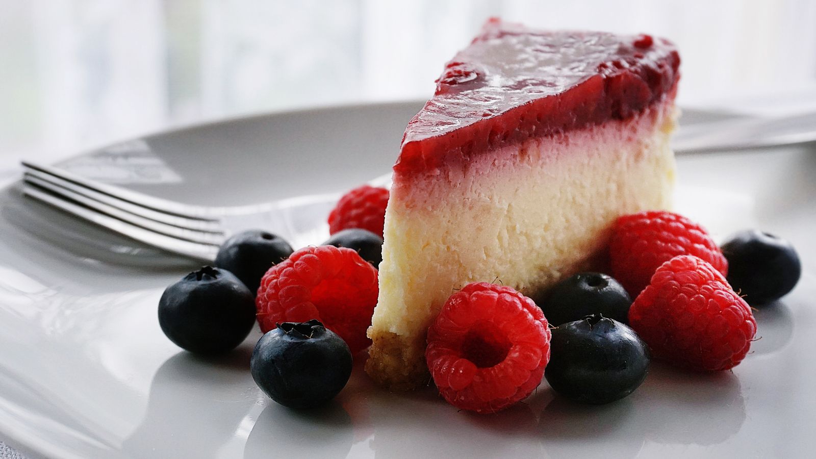 Part de cheesecake aux framboises avec coulis et fruits rouges